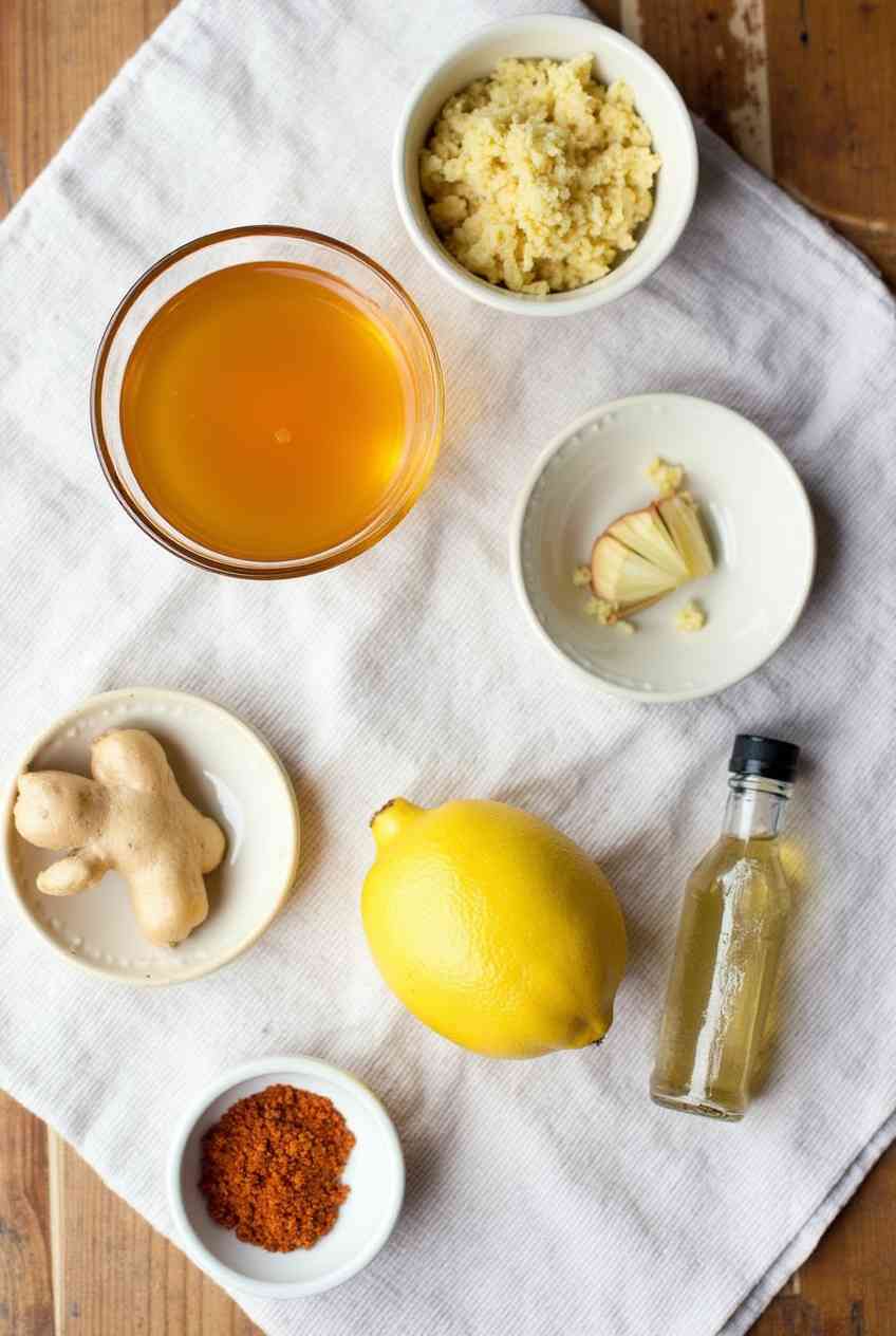Amish Amoxicillin Recipe - Best Homemade Natural 7 Flat lay of natural ingredients for Amish Amoxicillin: raw honey, fresh garlic, lemon, ginger, cayenne pepper, and apple cider vinegar.